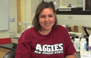 Student in New Mexico State Aggies shirt in a laboratory setting